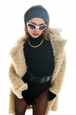 İleri moda genç bayan şık bir kış elbisesi içinde cesur aksesuarlarla poz veriyor.