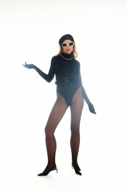 Şık bir kadın kendine güvenerek poz veriyor, kendine has tarzını parlak ışıkta sergiliyor..