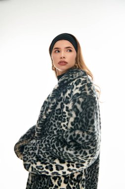 Genç bir kadın, rahat bir leopar desenli ceket ve şık aksesuarlara güvenir..