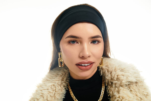 A young woman confidently showcases her unique style with elegant attire and bold accessories.