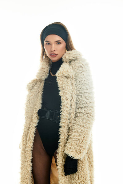 A bright backdrop showcases a stylish young woman in a luxury coat and chic accessories.