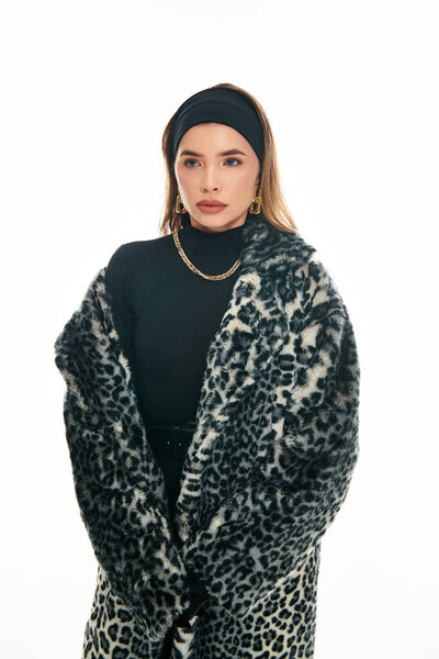 A beautiful young woman showcases her fashionable style in a leopard print coat and black top.