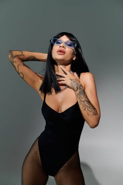 Kendine güvenen bir kadın, kendine has tarzını göz alıcı aksesuarları olan parlak siyah bir elbiseyle sergiliyor..