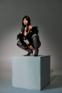 Kendine güvenen genç bir kadın şık bir kaide üzerinde, çarpıcı bir moda gösterisi sergiliyor..