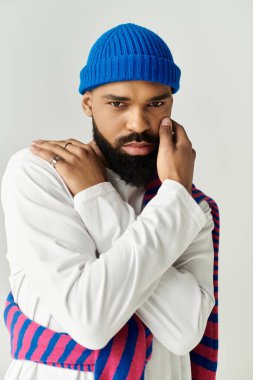 Yumuşak ışık altında, karizmatik bir adam modaya uygun kıyafetini sergiliyor, stil ve güven saçıyor..