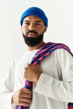 Şık bir genç adam kendine güvenen renkli bir eşarbı tutarken benzersiz görünüşünü sergiliyor..