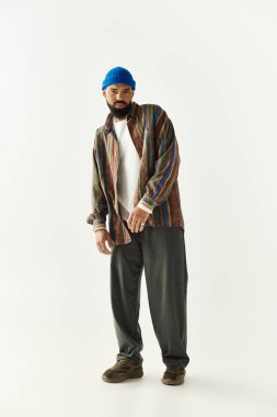 Genç adam parlak bir arka plana karşı şık bir kıyafet sergiliyor, tarzını vurguluyor..