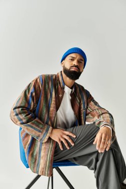 Yakışıklı bir erkek model otururken hiç zorlanmadan modaya uygun kıyafetler sergiliyor..