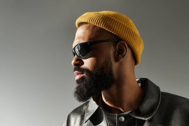 Tarafsız bir arkaplanda şık giyinmiş bir adam şık görünüşünü sergiliyor..