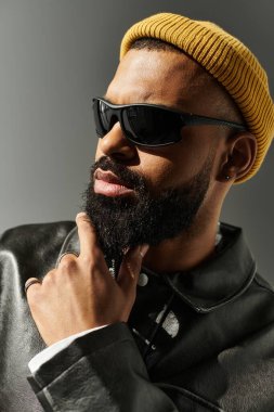 Şık bir adam kendine güvenerek poz veriyor, modasını minimalist bir arkaplanda sergiliyor..