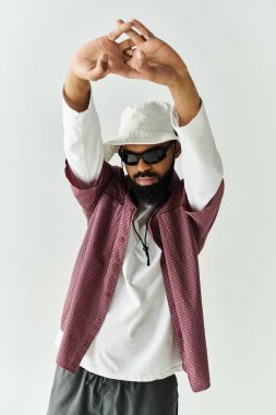 Tarz sahibi genç bir adam minimalist bir stüdyoda, modaya uygun bir hava ve cazibe yayarak poz veriyor..