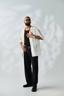 Şık bir adam kendine güvenerek canlı bir ortamda poz verir, eşsiz kıyafetini sergiler..