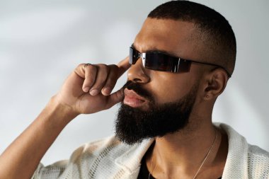 Şık bir genç adam şık güneş gözlükleriyle düşünceli bir şekilde poz verir, zarif bir yerde karizma yayar..