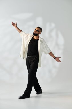 Genç ve şık bir adam şık bir kıyafetle, modaya uygun görünüşünü ve havasını sergileyerek özgüvenle poz verir..