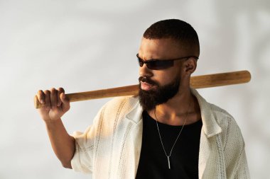 Yakışıklı genç adam bir beysbol sopası tutuyor, şehir ortamında eşsiz bir moda anlayışı sergiliyor..