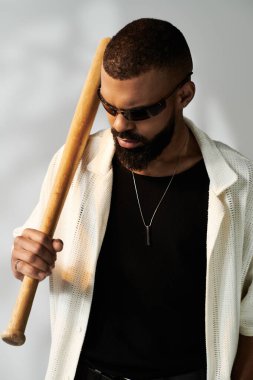 Genç bir adam, elinde beyzbol sopasıyla moda anlayışını sergiliyor. Kendine güveni ve tarzı var..