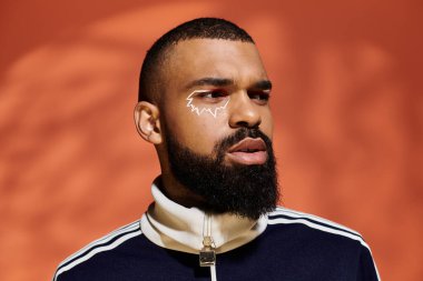 Yakışıklı genç adam benzersiz makyaj ve gün ışığında şık bir kıyafetle moda anlayışını sergiliyor..