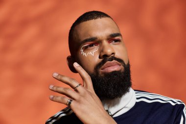 Çekici makyajlı yakışıklı genç adam, özgüvenle poz veriyor..