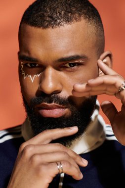 Şık bir genç adam kendine güveni canlı bir arkaplan karşısında çarpıcı bir yüz tasarımı ile yayar..