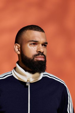 Yakışıklı genç adam çarpıcı bir ifadeyle gururla duruyor, sanatsal yeteneğini ve tarzını sergiliyor..