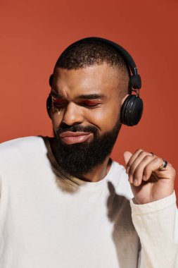 Şık görünümlü genç adam kulaklıklı, parlak ve cesur bir müzik dinliyor..