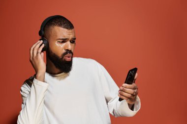 Çekici sakallı yakışıklı adam telefonunu kontrol ederken dikkatlice müzik dinliyor..