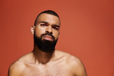 Modayı takip eden genç adam, canlı bir arka planda eşsiz bir yüz boyası sergiliyor..