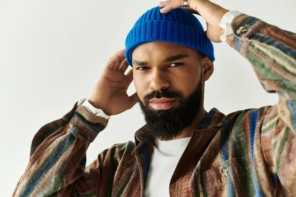 Yakışıklı genç adam mavi beresini renkli ve modaya uygun bir kıyafet giyerken ayarlıyor..