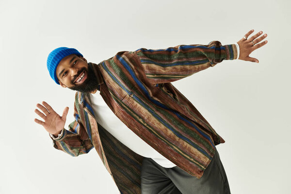 Молодой человек демонстрирует свое чувство стиля с красочным костюмом и игривым поведением во время позирования.