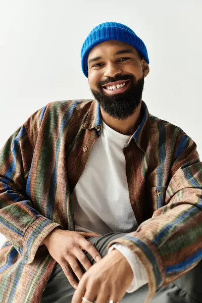 Yakışıklı adam rahat bir şekilde oturur, neşeli bir gülümseme ve rahat bir tavırla moda anlayışı gösterir.