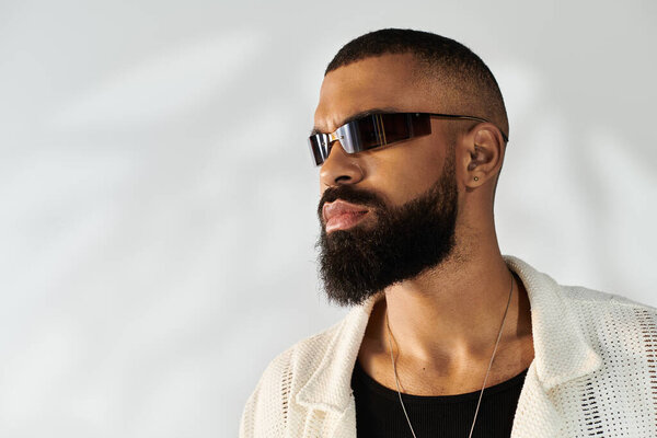 The young mans stylish look shines in modern attire against a simple backdrop.