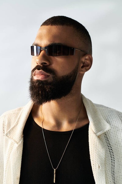 A charming man in trendy sunglasses and stylish attire shines in a bright setting.