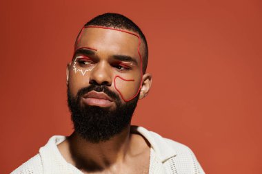 Şık bir genç adam sıcak bir arkaplanda yüz sanatını sergiliyor..