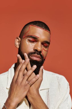 Yakışıklı genç bir adam kendine güvenerek poz veriyor. Sıcak bir ortamda çarpıcı bir yüz sanatıyla..