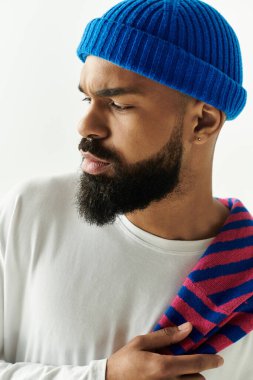 Tarz sahibi genç bir adam özgüvenle poz veriyor, özgün görünüşünü sade bir arka plana vurguluyor..