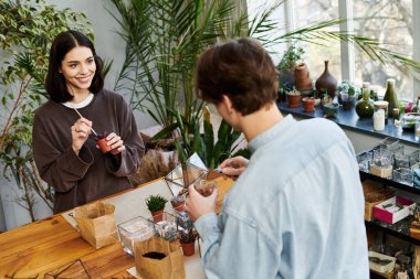 Yaratıcı çift bir sanat stüdyosunda neşe içinde küçük bitkiler yetiştiriyor ve yetiştiriyor..