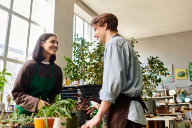 Yaratıcı çift, yeşillik ve sanat eserleriyle çevrili canlı bir stüdyoda neşe içinde iş birliği yapıyor..