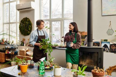 Yaratıcı çift neşeli bir şekilde bitkileri besliyor ve canlı bir sanat stüdyosunda fikirlerini paylaşıyor.