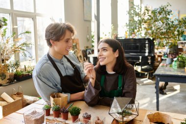 Yaratıcı çift, canlı bir sanat stüdyosunda proje üzerinde çalışırken kahkahalarını ve fikirlerini paylaşıyor..