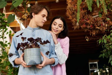 Genç çift, güneşli bir stüdyoda bitki ve dekor arasında sanat yaratıyor..