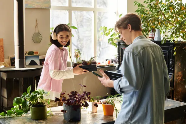 İki genç sanatçı renkli ve canlı bir stüdyoda bitki yetiştirme ve fikir alışverişinde bulunuyor..