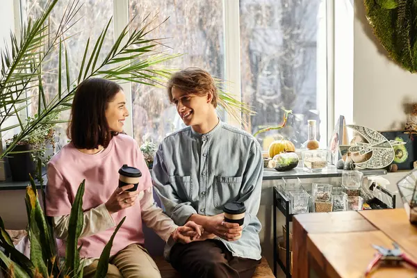 Genç çift bir sanat stüdyosunda keyifli bir anı paylaşıyor, kahvelerini yudumluyor ve fikir alışverişinde bulunuyor..