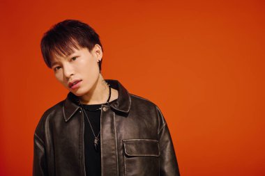 Genç Asyalı adam tarzını sergiliyor, siyah deri ceket giyiyor, kendine güveni ve çekiciliği var..