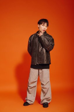 Kendine güvenen genç adam göz alıcı bir deri ceketle göz alıcı renkler sergiliyor..