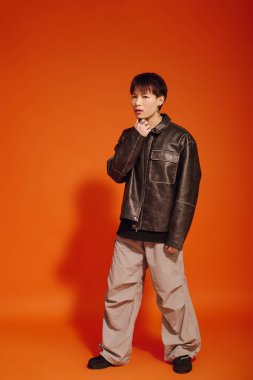 Yakışıklı genç bir adam şık deri ceketi ve rahat pantolonuyla moda anlayışını sergiliyor..