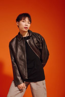 Genç, yakışıklı Asyalı bir adam parlak turuncu bir zemin üzerinde duruyor..