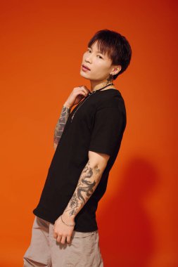 Şık bir genç adam şık kıyafetini canlı turuncu bir duvarla ayarlıyor..