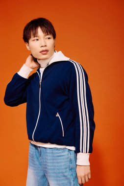 Yakışıklı genç adam şık giyiniyor modern moda, canlı turuncu bir duvara karşı..