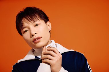 Şık bir genç adam canlı turuncu bir arka plana karşı özgüvenle poz verir..