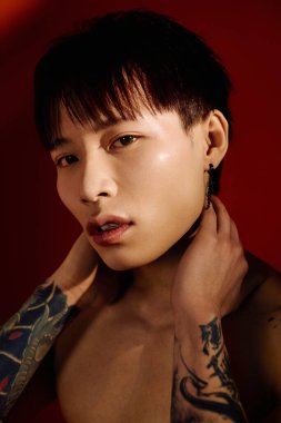 Yakışıklı bir Asyalı çekici bir şekilde boynuna dokunur cesur, sanatsal bir şekilde..